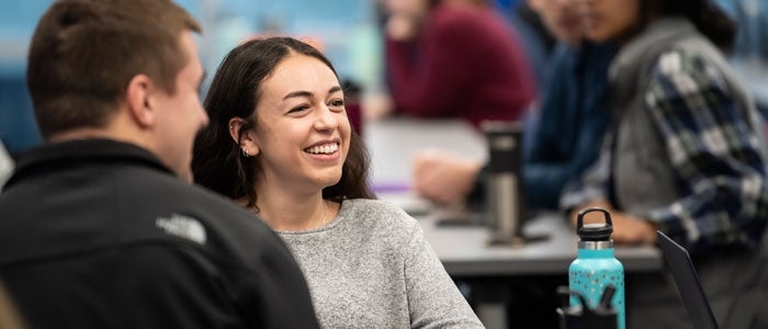 A students smiles while talking with classmates 