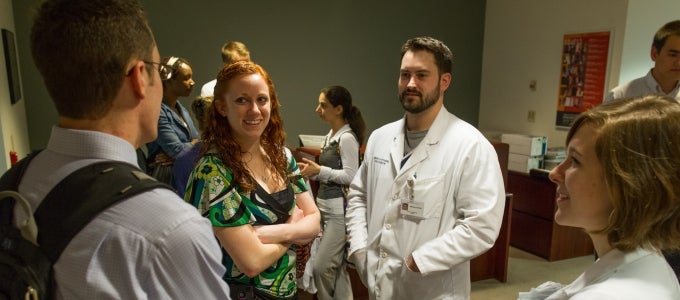 men and women in white lab coats conversing 