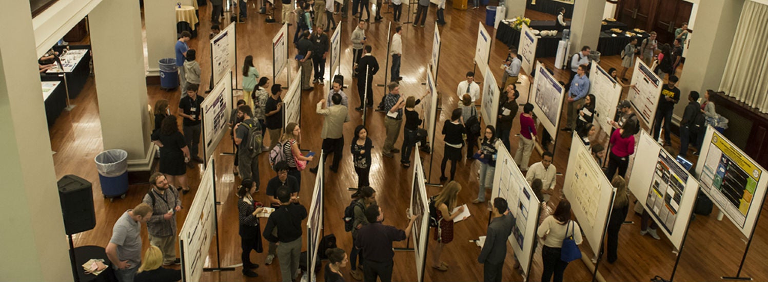 group of people viewing research posters in auditorium 