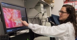 woman in lab using computer and microscope 