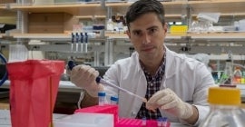 man in lab coat using pipet 