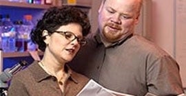 woman with glasses and man reading papers