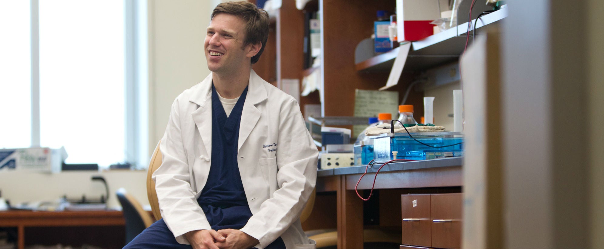 man in white coat sitting in lab 